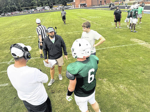 Easley Quarterback Coach/Offensive Coordinator Matt Stack and runningbacks coach Clint Freeman talk things over with senior Kaden Cooper (No. 6) at a recent scrimmage in Powdersville. 
                                 Mark Beery | For The Progress